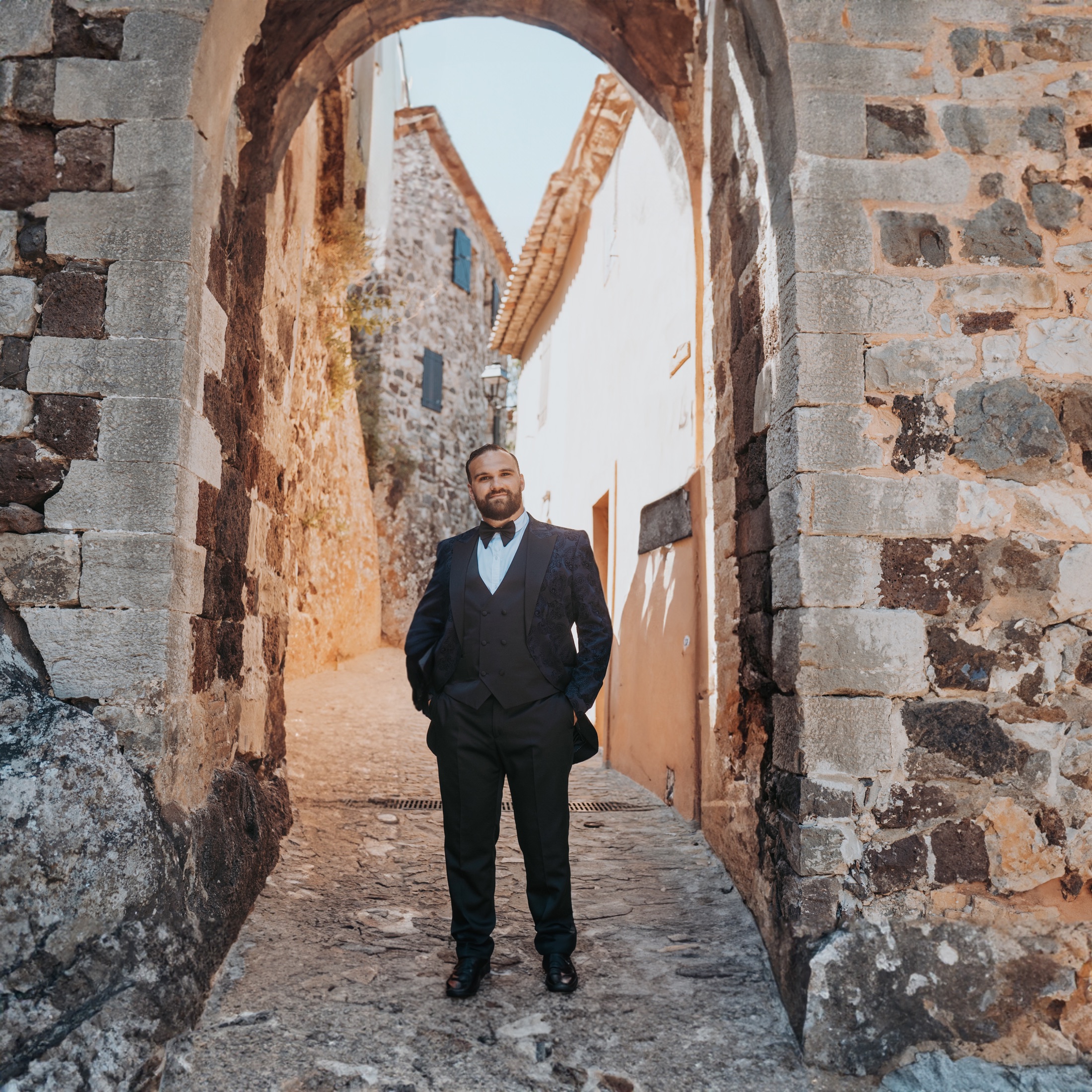 Kyle, creator of Chez Sophie, standing beneath a sunlit stone arch